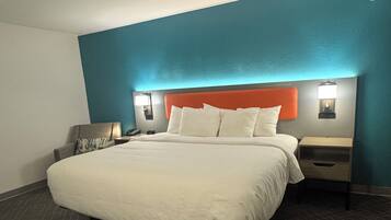 Una habitación de hotel con una cama grande, una mesita de noche con lámpara y una lámpara de pared.