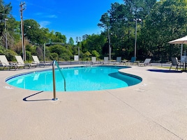 Una piscina con sillas de descanso y un cartel que prohíbe el clavado.