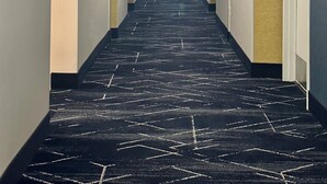 A hotel hallway with a carpeted floor, light-colored walls, and doors on both sides.