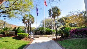 A landscaped area with a paved walkway, palm trees, and a building with a dome structure in the background. - Hampton Inn Charleston-Historic District (Charleston)
