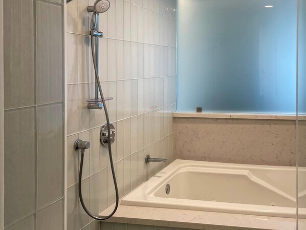 A bathroom with a bathtub, a shower with a handheld showerhead, and a window above the bathtub. - The Volare, an Ascend Collection Hotel (San Clemente)