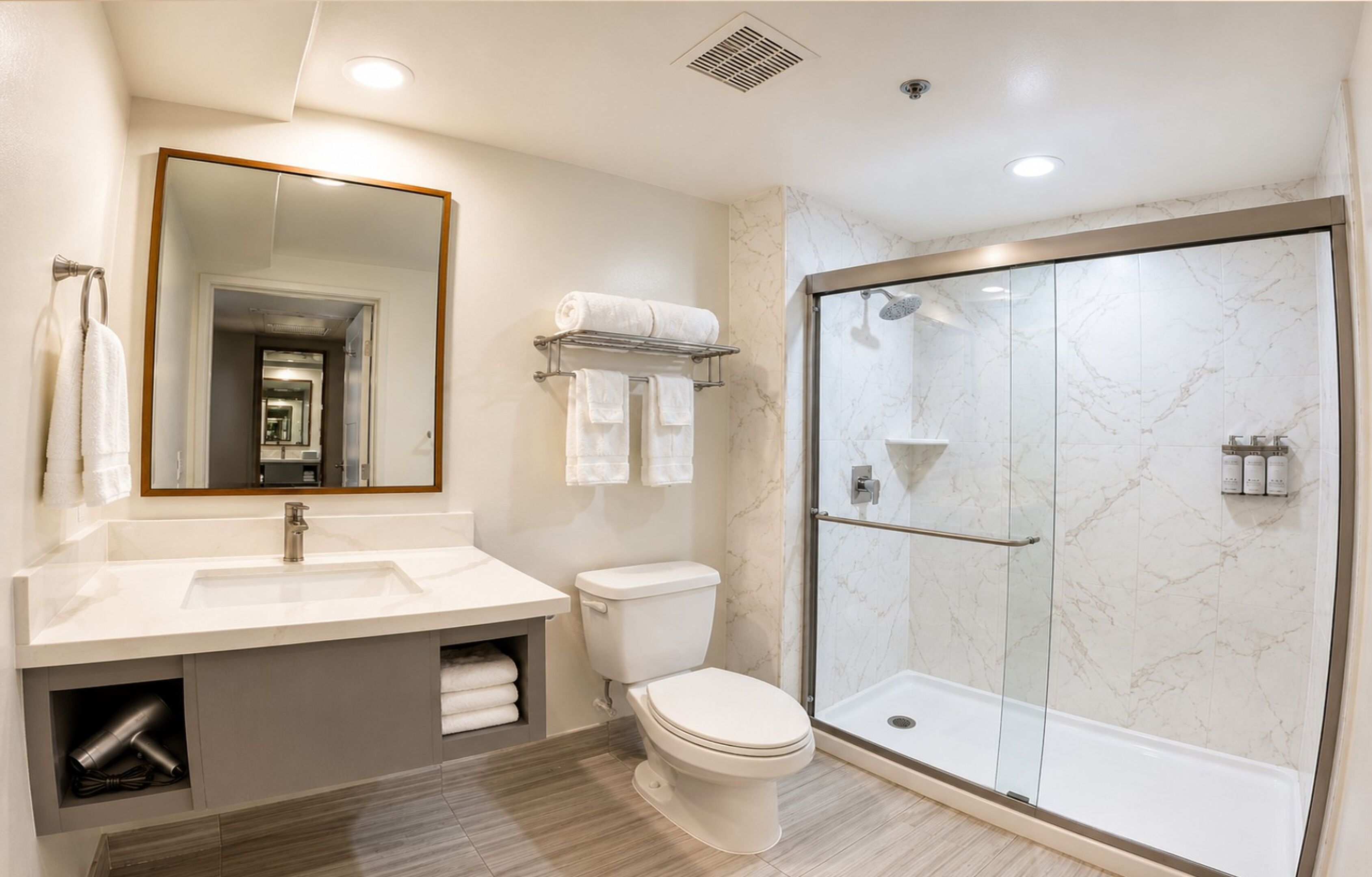 A modern bathroom with a large mirror, a sink, a toilet, and a glass-enclosed shower.