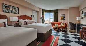 A hotel room with two beds, a sofa, a desk, and a view of the city.