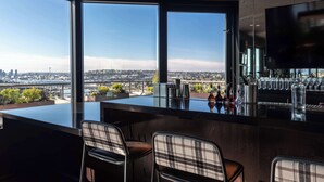 A modern bar with large windows offering a city view. - Graduate by Hilton Seattle (Seattle)
