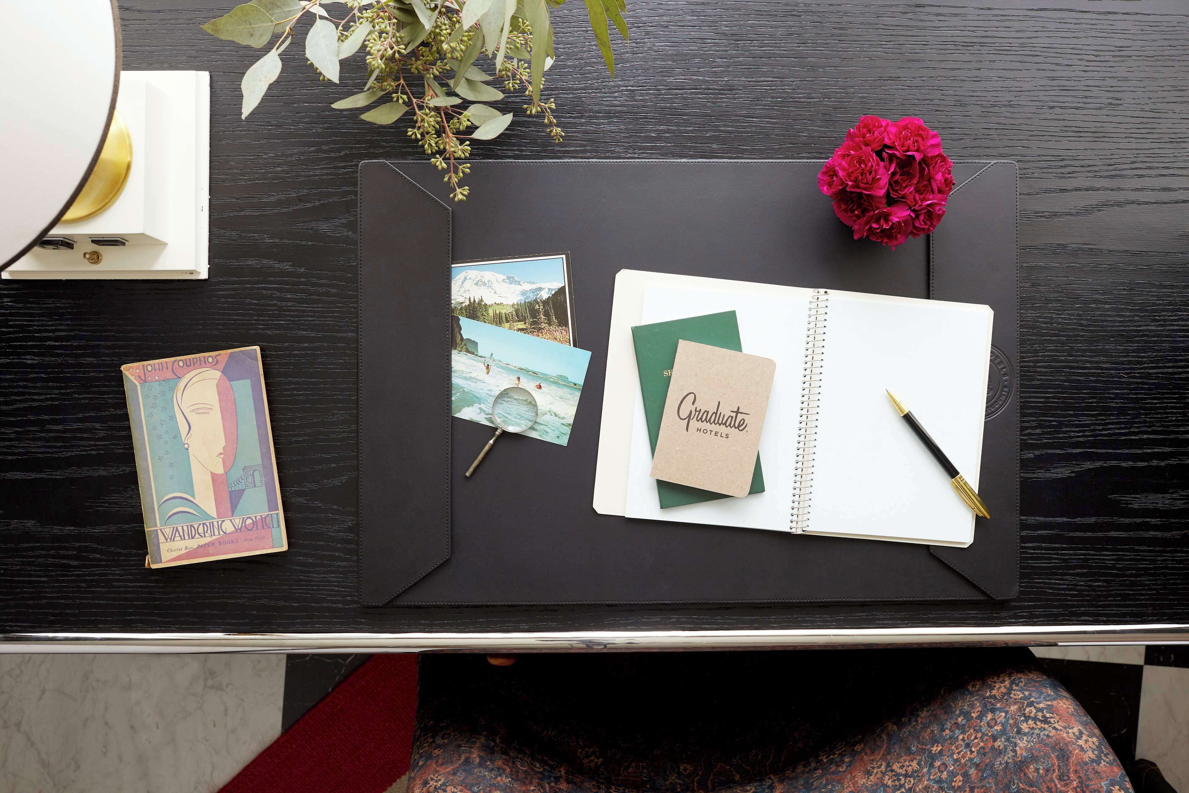 Ein Schreibtisch mit Notizbuch, Stift, Karte und kleiner Fotoecke.