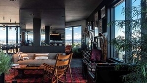 A modern living room with a large window, a sofa, a rocking chair, and a coffee table. - Graduate by Hilton Seattle (Seattle)
