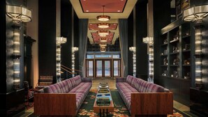 A lobby with two sofas facing a central coffee table, flanked by tall lamps and a bookshelf with decorative items. - Graduate by Hilton Seattle (Seattle)