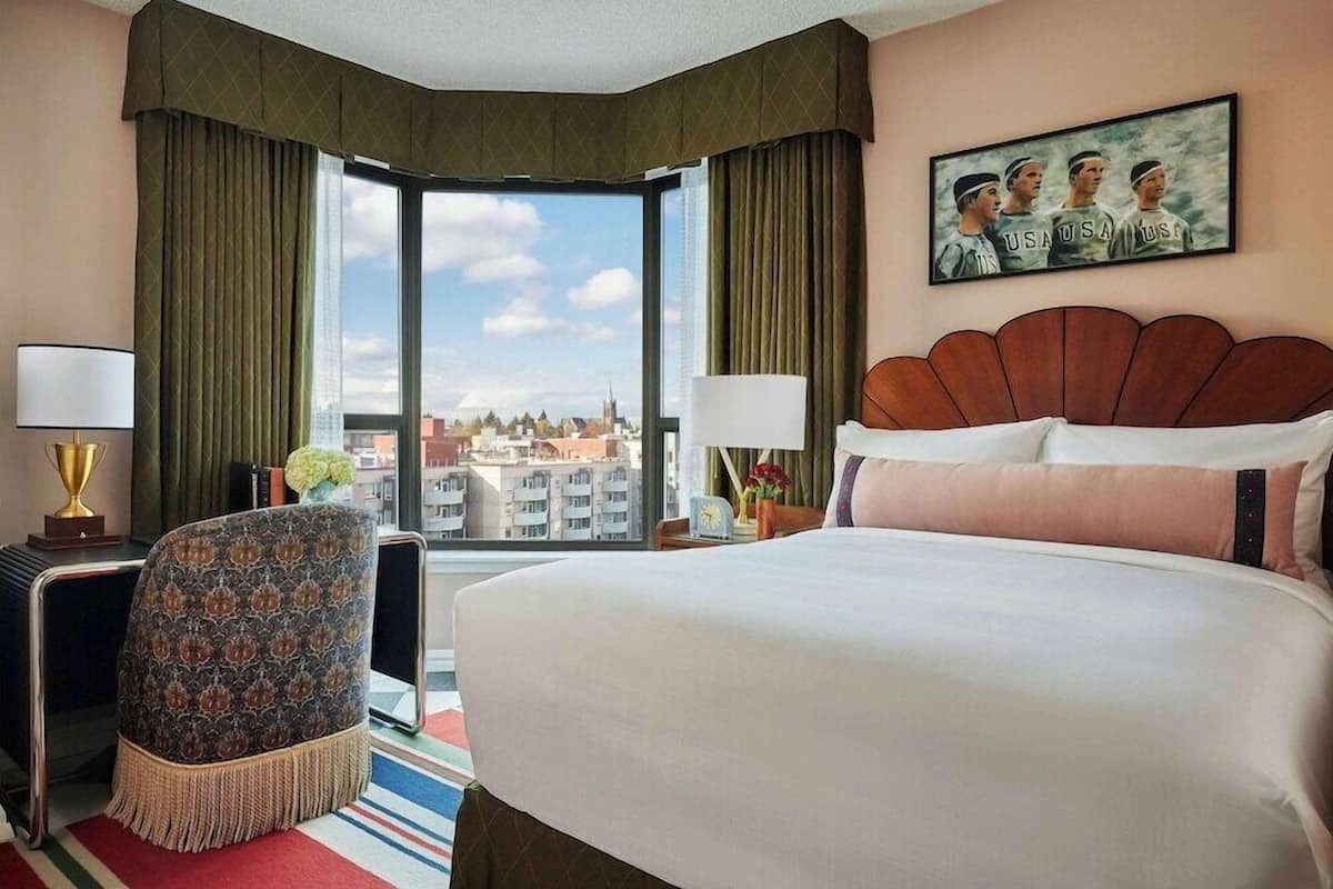 Une chambre d’hôtel avec un grand lit, une chaise, un bureau et une vue sur la ville.