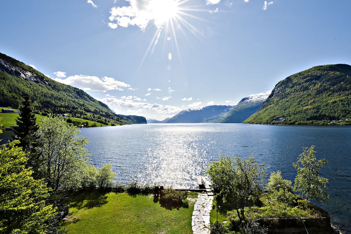 A serene lake surrounded by lush green hills and a clear sky.