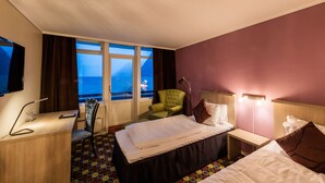 Habitació d'hotel amb un llit gran, una taula, una cadira i una televisió.