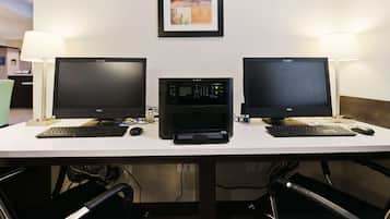 Un bureau avec deux écrans, une imprimante et deux claviers.
