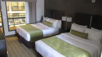 Une chambre d’hôtel avec deux lits, un bureau et une fenêtre donnant sur un immeuble.
