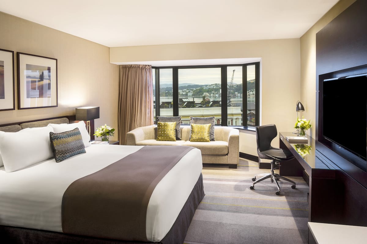 Une chambre d’hôtel avec un grand lit, un bureau, une chaise et un téléviseur.
