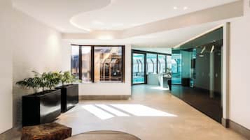 A modern hotel lobby with a curved ceiling, large windows, and a seating area with a glass table.