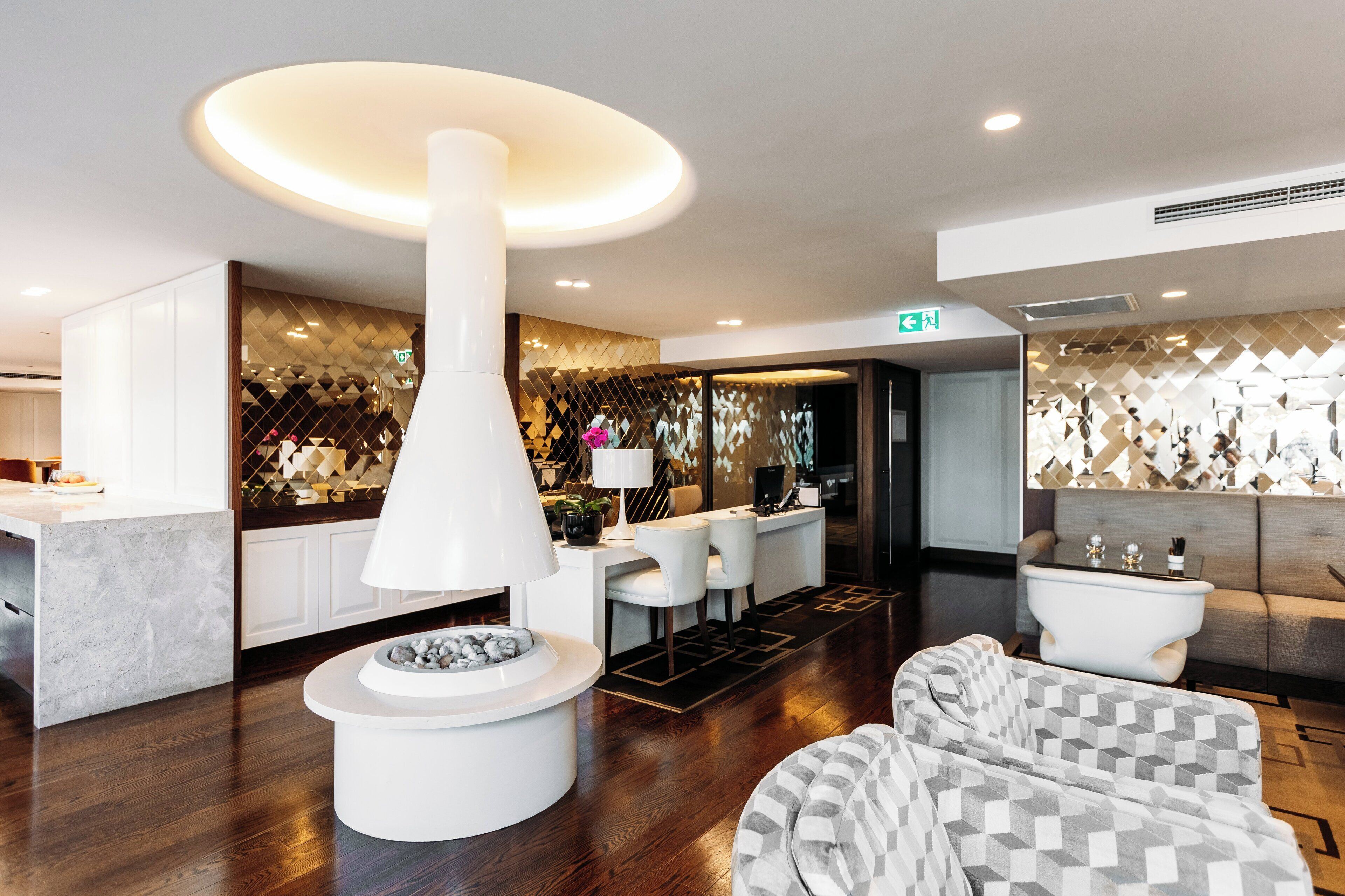 A modern hotel lobby with a central white column, seating area, and a reception desk.