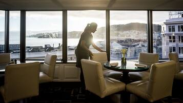 A room with large windows, a view of the city, and a table with chairs.
