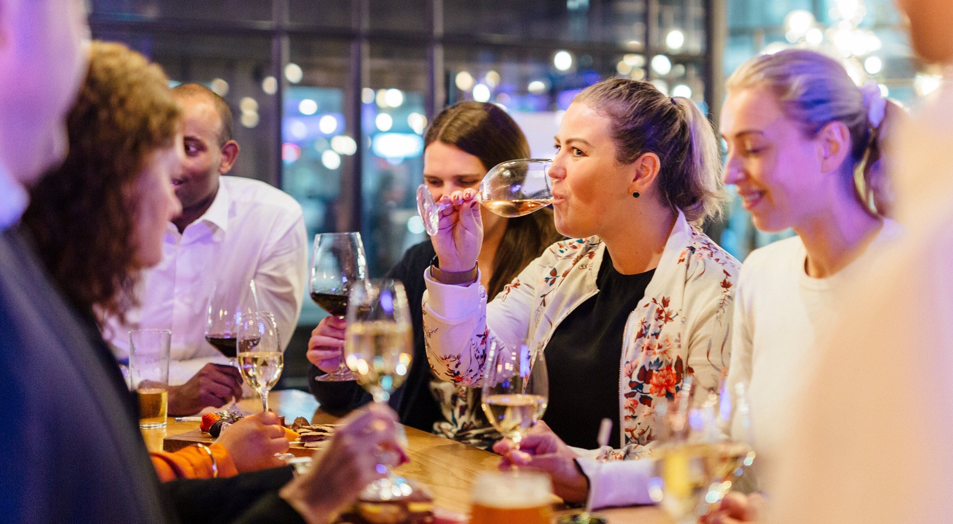 A group of people seated around a table with wine glasses, suggesting a social gathering or event.