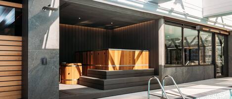 A modern outdoor pool area with a built-in sauna, a wooden bench, and a metal ladder.