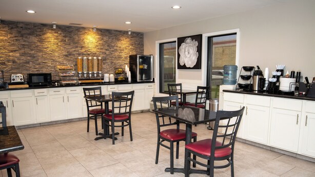 A modern kitchen with white cabinets, a stone backsplash, and a dining area with a table and chairs.