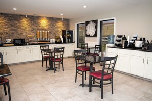 A modern kitchen with white cabinets, a stone backsplash, and a dining area with a table and chairs.