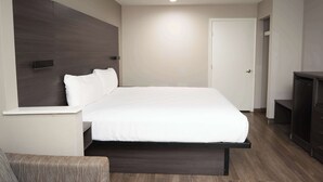 A modern hotel room with a large bed, a bedside table, a wardrobe, and a door.