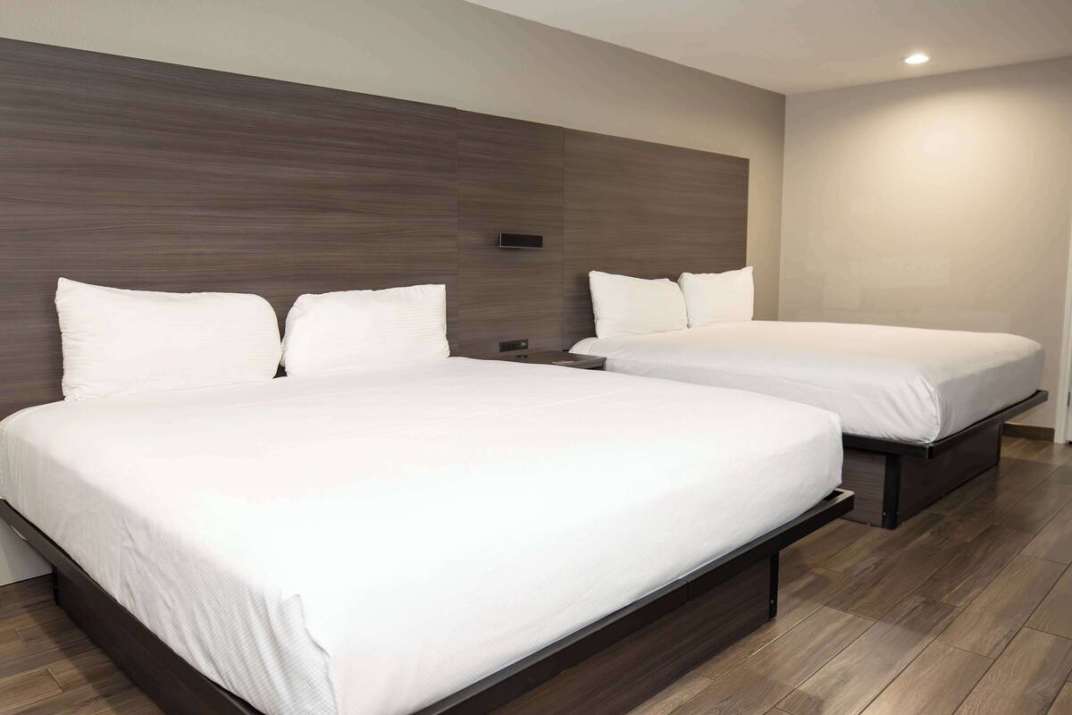 A hotel room with two beds, a wooden headboard, and a modern design.