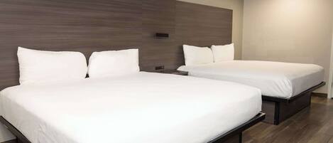 Habitación de hotel con dos camas, cabecero de madera y diseño moderno.