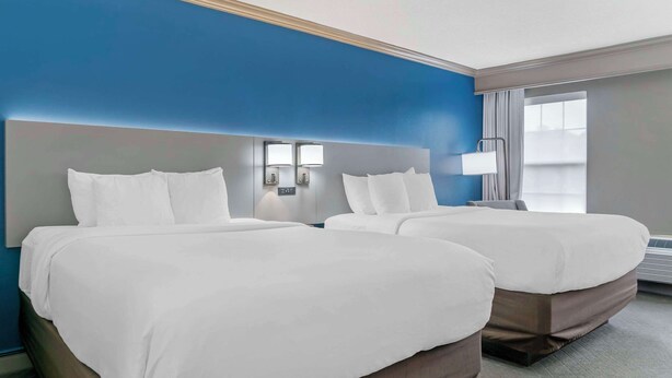 Una habitación de hotel con dos camas, un ventanal grande y una pared azul decorativa.