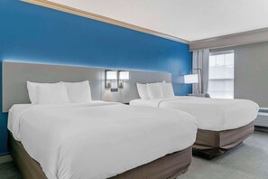 Una habitación de hotel con dos camas, un ventanal grande y una pared azul decorativa.