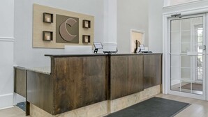 Un mostrador de recepción de diseño moderno, un cartel de bienvenida y una puerta de cristal que da al exterior.