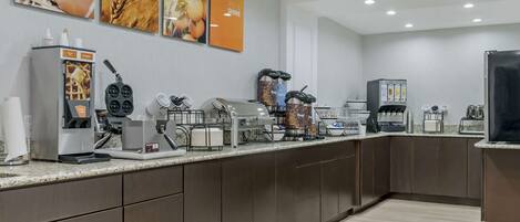 Une cuisine moderne dotée d’un espace dédié au café, comprenant une machine à café, un moulin et différents types de dosettes de café.