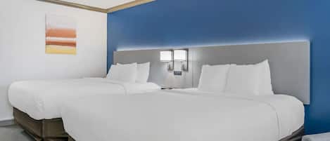 Una camera d'albergo con due letti, una parete azzurra e un quadro appeso al muro.