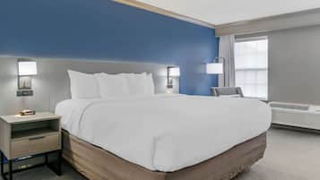 Una habitación de hotel con una cama grande, mesitas de noche y una ventana con cortinas.