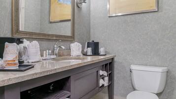 A bathroom with a marble sink, a toilet, and a mirror.