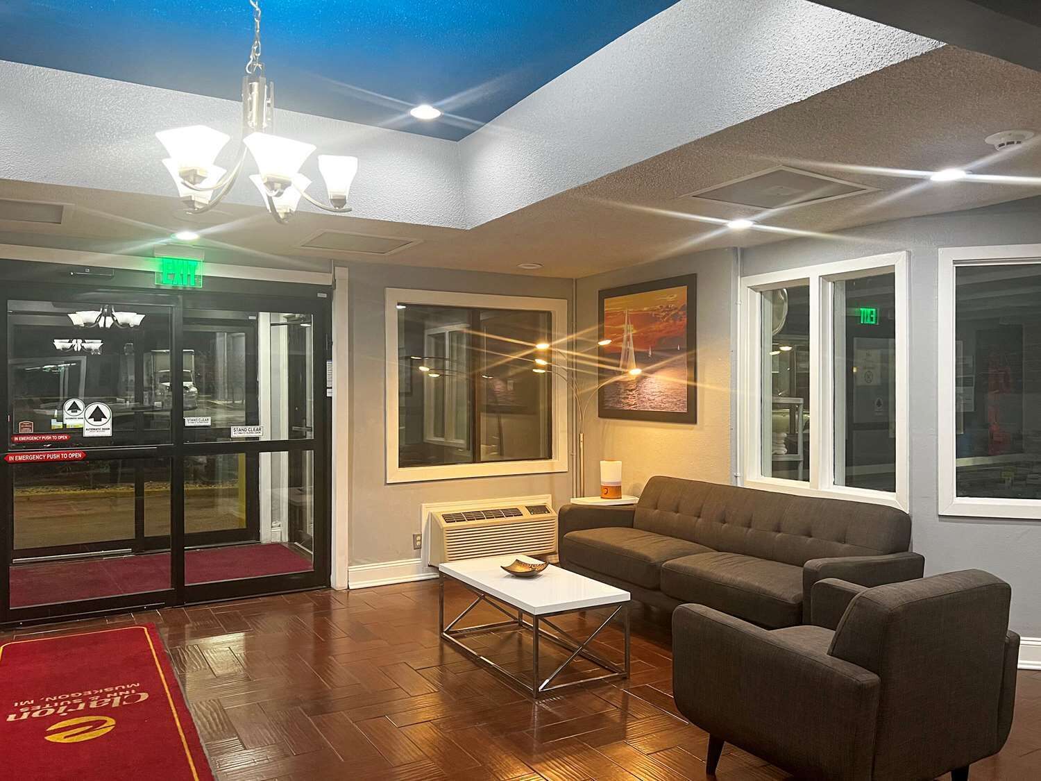 A lobby with a reception desk, a sofa, a coffee table, and a painting on the wall.