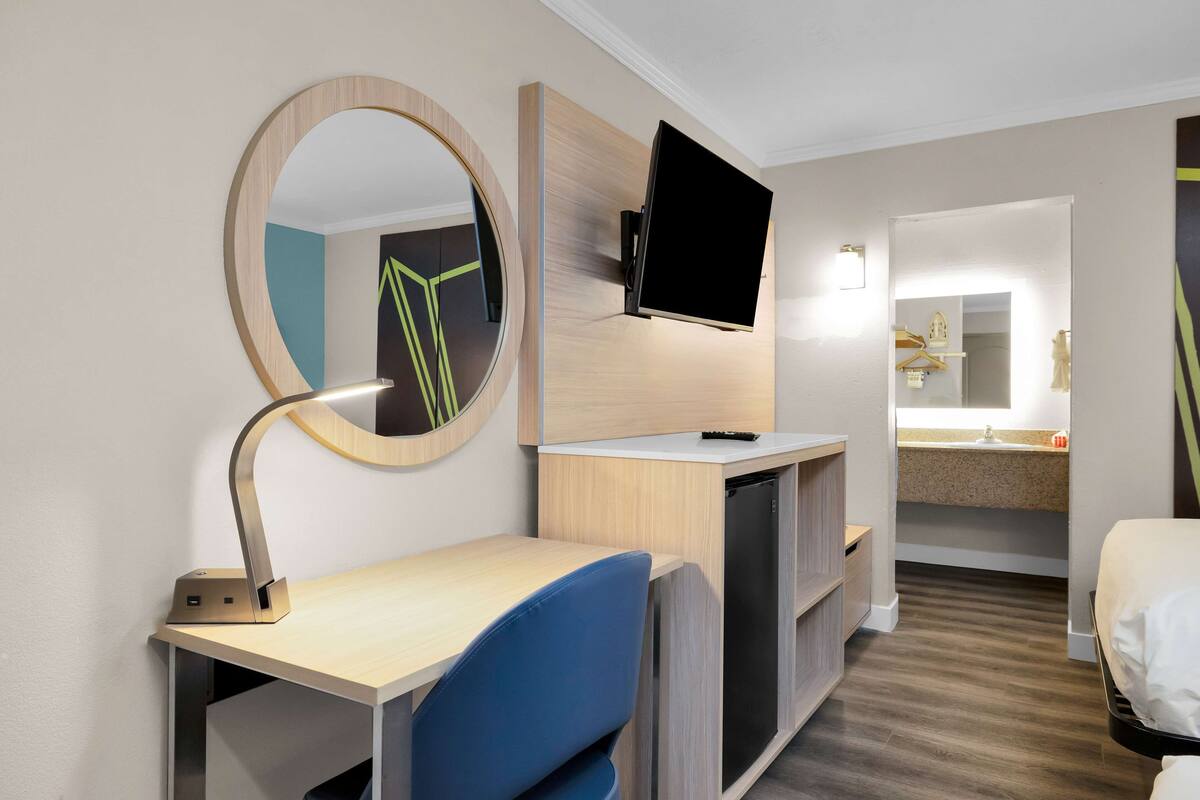 Hotellihuone, jossa on työpöytä, tuoli, televisio ja peili.