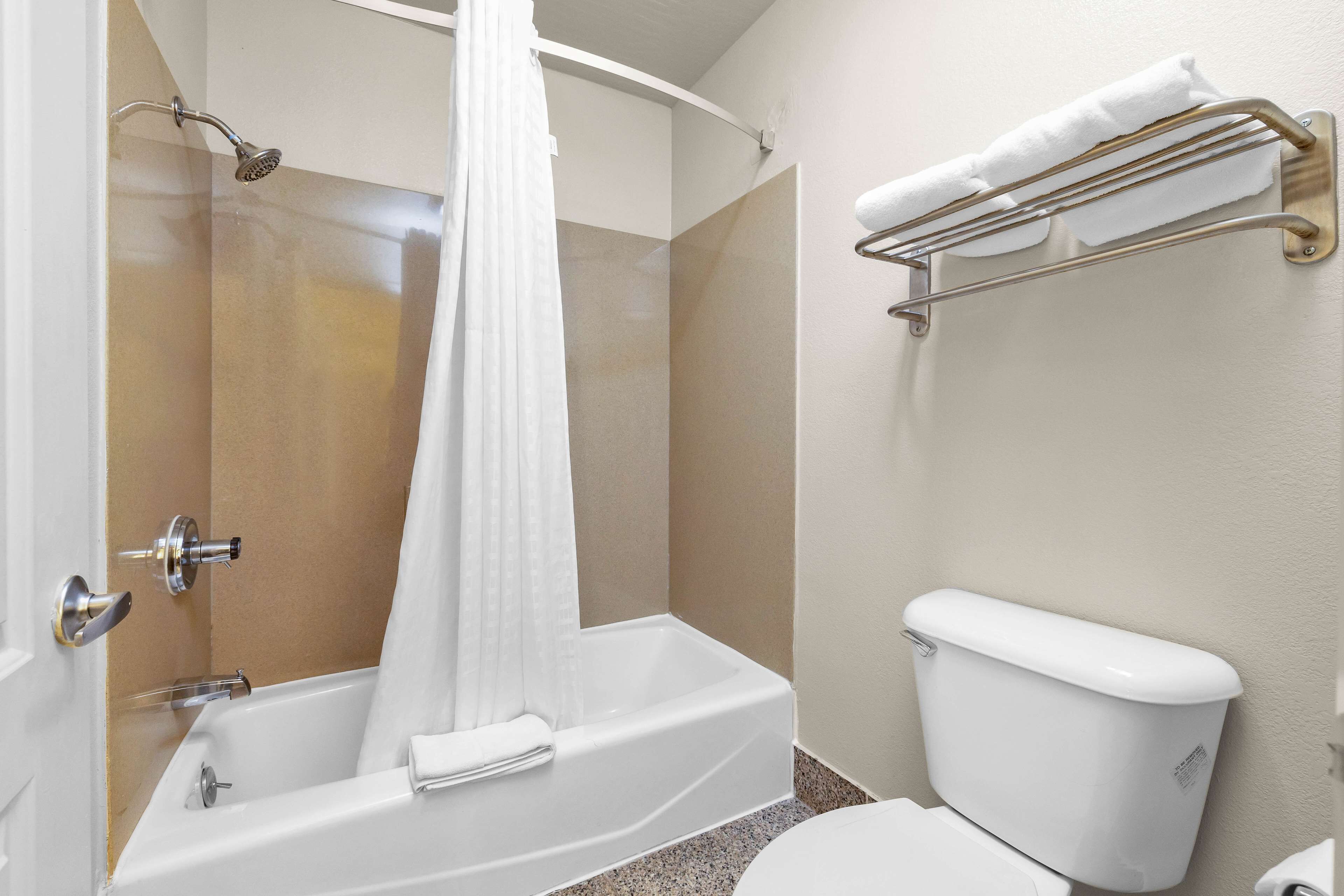 A bathroom with a bathtub, shower, toilet, and a towel rack.