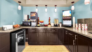 Una cocina equipada con cafetera, microondas y refrigerador.
