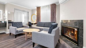 Una sala de estar moderna con chimenea, sofás grises, una mesa de centro y una luz de aro en la pared.