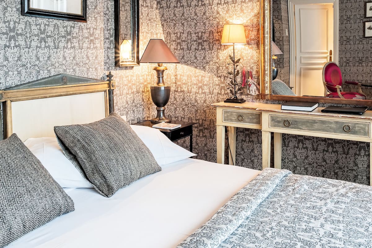 Une chambre d’hôtel comprenant un lit, une table de chevet avec une lampe, un miroir et une commode.