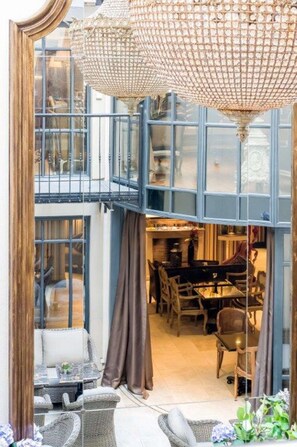 A multi-level room with a chandelier, wicker furniture, and a dining area. - Hôtel Chateaubriand Champs Elysées (Paris)