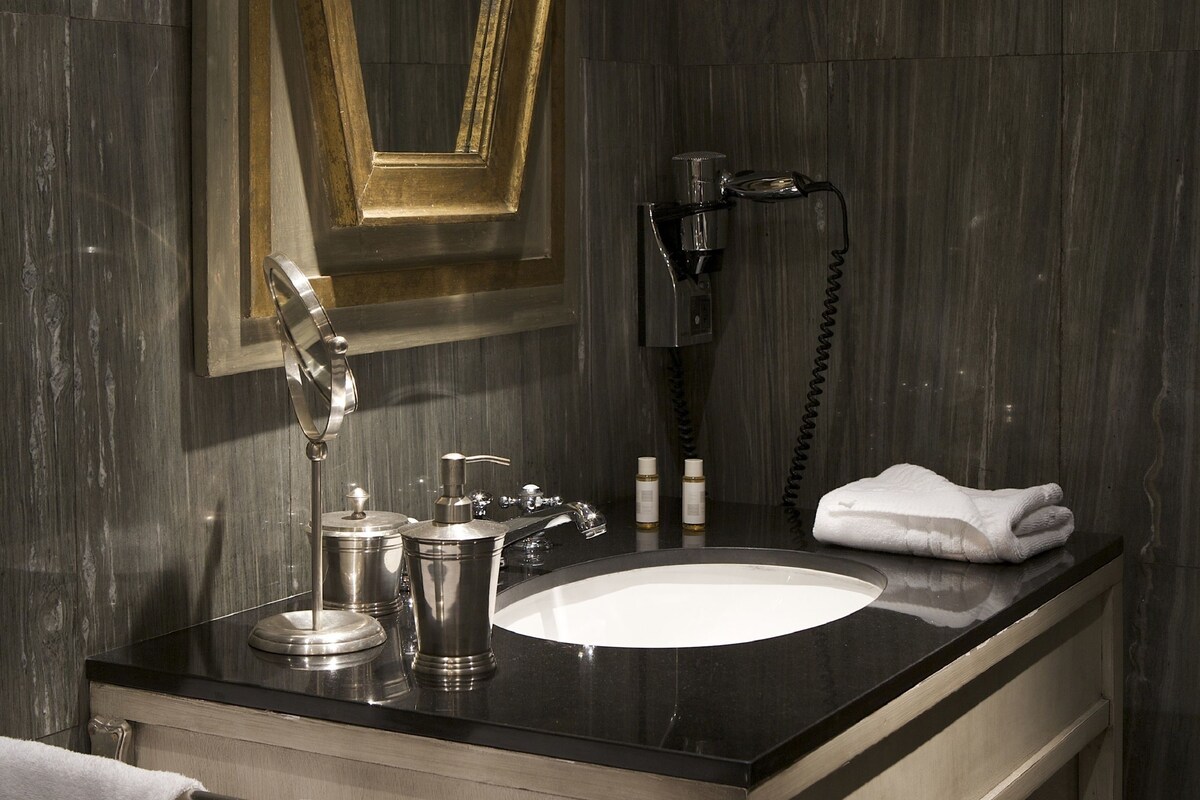 Une salle de bain avec un grand miroir, un lavabo, un sèche-cheveux et des serviettes.