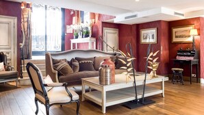Een woonkamer met een bank, stoelen, een salontafel en een open haard.