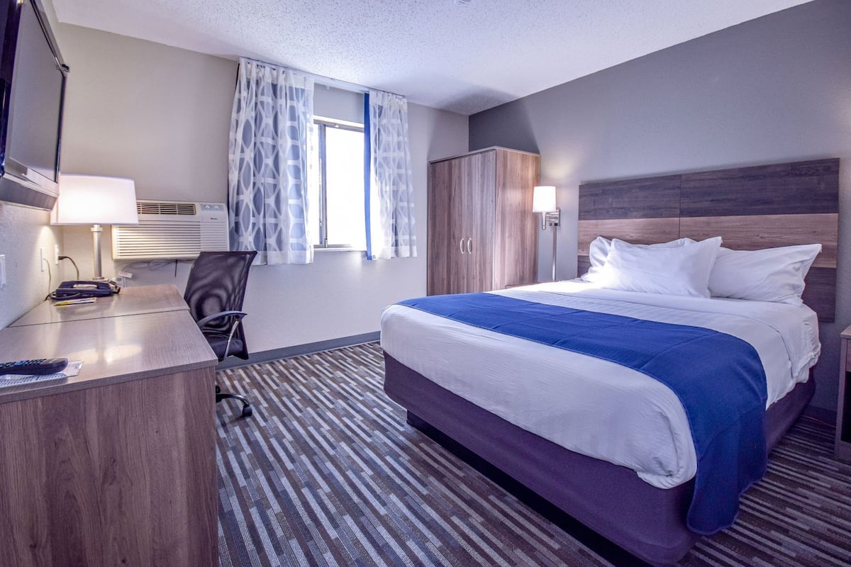 A hotel room with a bed, desk, chair, and wardrobe.