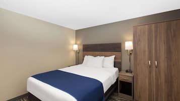 Una habitación de hotel con una cama grande, dos lámparas de noche, un armario y una mesita con una radio.