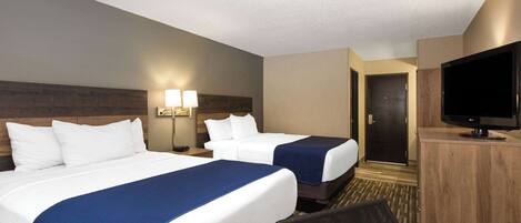A hotel room with two beds, a television, and a desk.