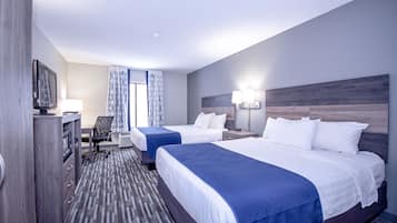 A hotel room with two beds, a desk, a chair, a TV, and a window with curtains.