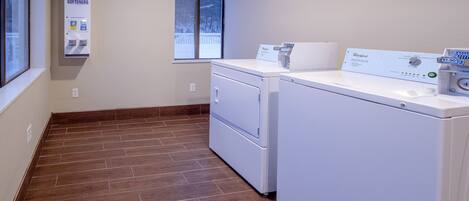 A laundry room with a washer and dryer, a window, and a sign about soap and bleach softeners.