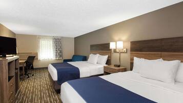 A hotel room with two beds, a desk with a chair, a TV, and a window with curtains.