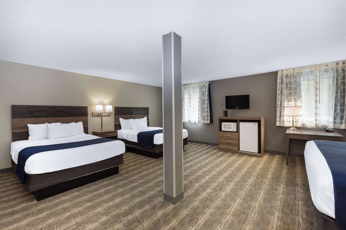A hotel room with two beds, a desk, a TV, and a minibar.